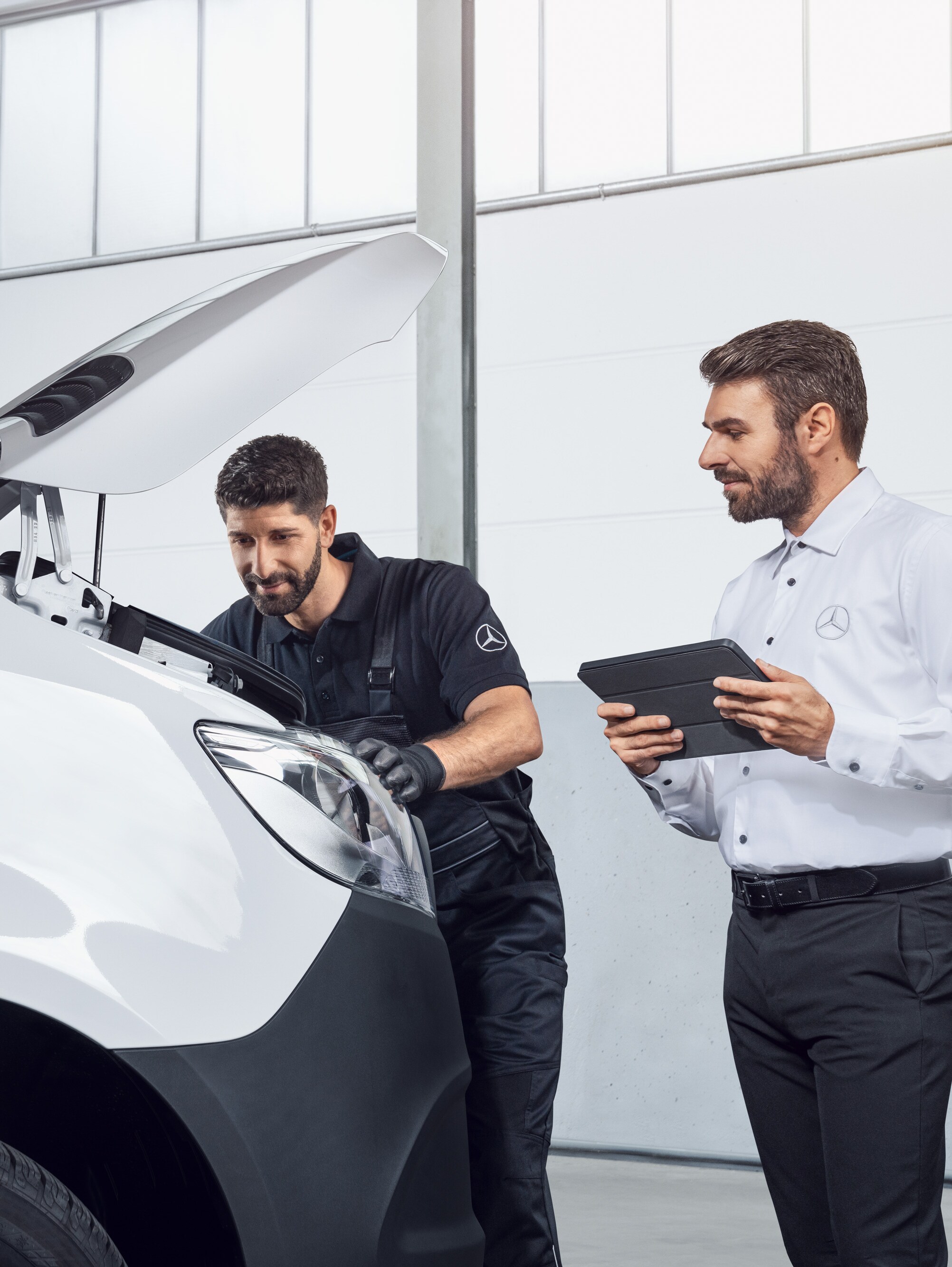 Dva muži testují Mercedes Sprinter s&nbsp;tabletem a&nbsp;otevřenou kapotou, téma: náhradní díly pro Mercedes-Benz Sprinter.