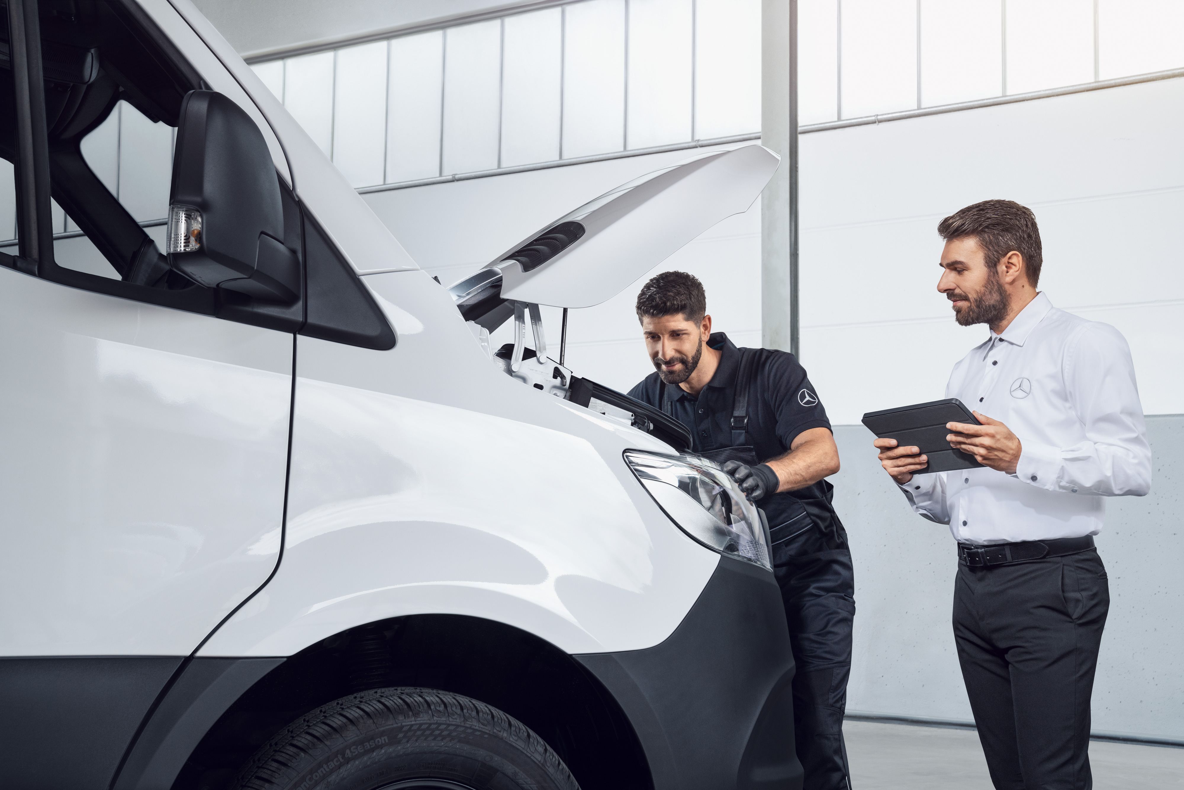 Mercedes-Benz | Kvalita originálních dílů pro dodávková vozidla Dva muži testují Mercedes Sprinter s tabletem a otevřenou kapotou, téma: náhradní díly pro Mercedes-Benz Sprinter.