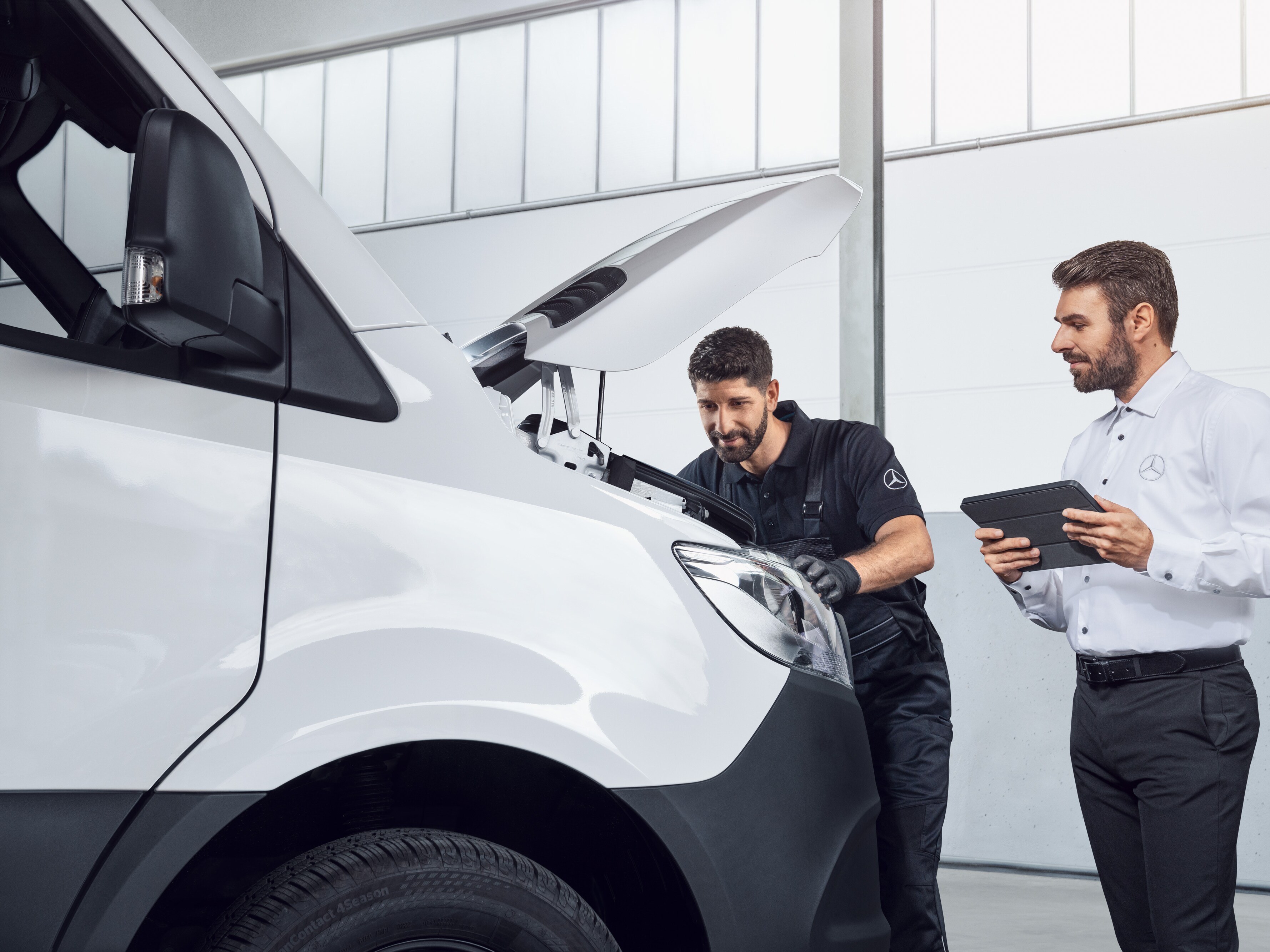 Dva muži testují Mercedes Sprinter s&nbsp;tabletem a&nbsp;otevřenou kapotou, téma: náhradní díly pro Mercedes-Benz Sprinter.