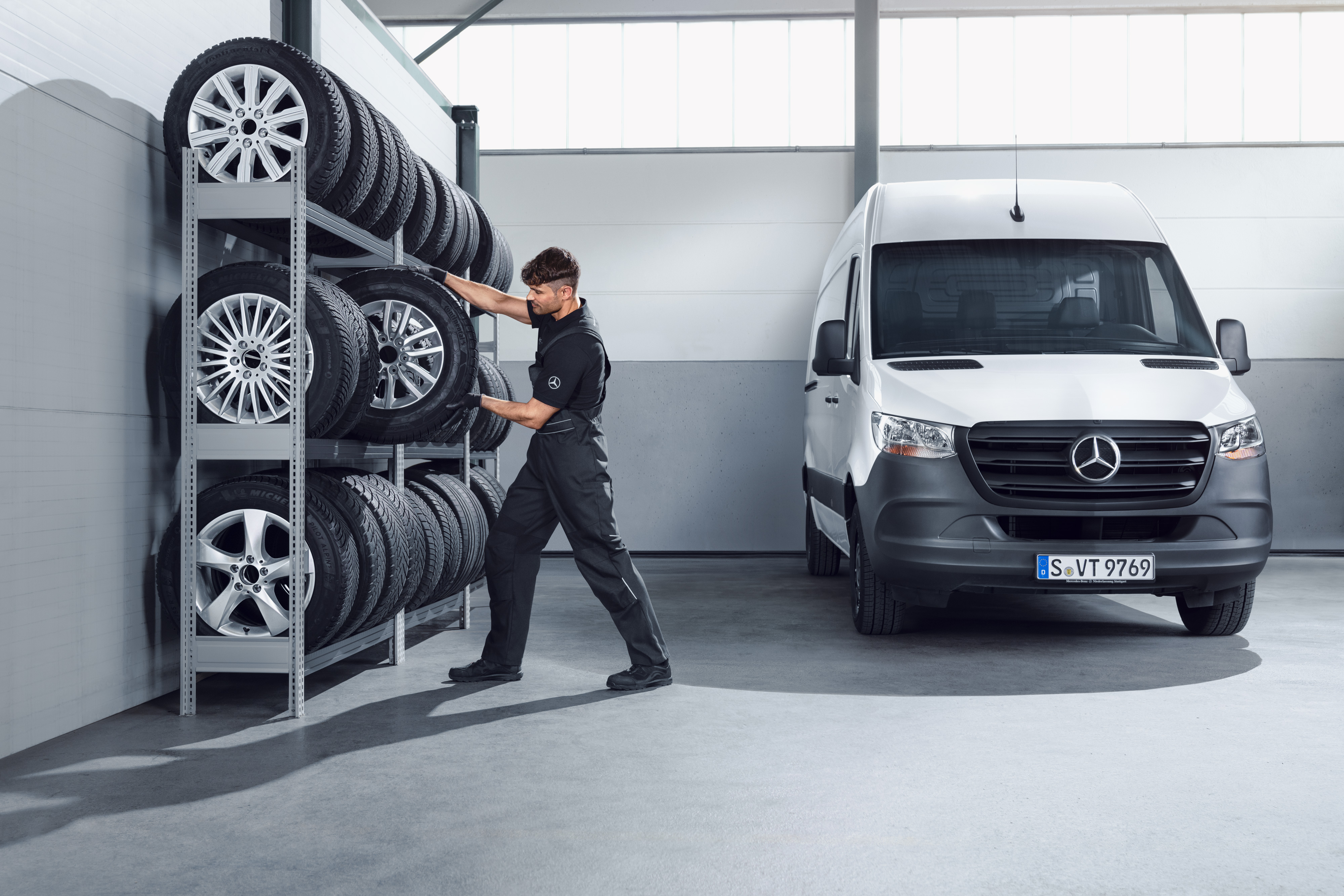 Mercedes-Benz | Kvalita originálních dílů pro dodávková vozidla Mechanik vybírá z police v dílně kompletní zimní kola Mercedes-Benz pro bílý Sprinter.