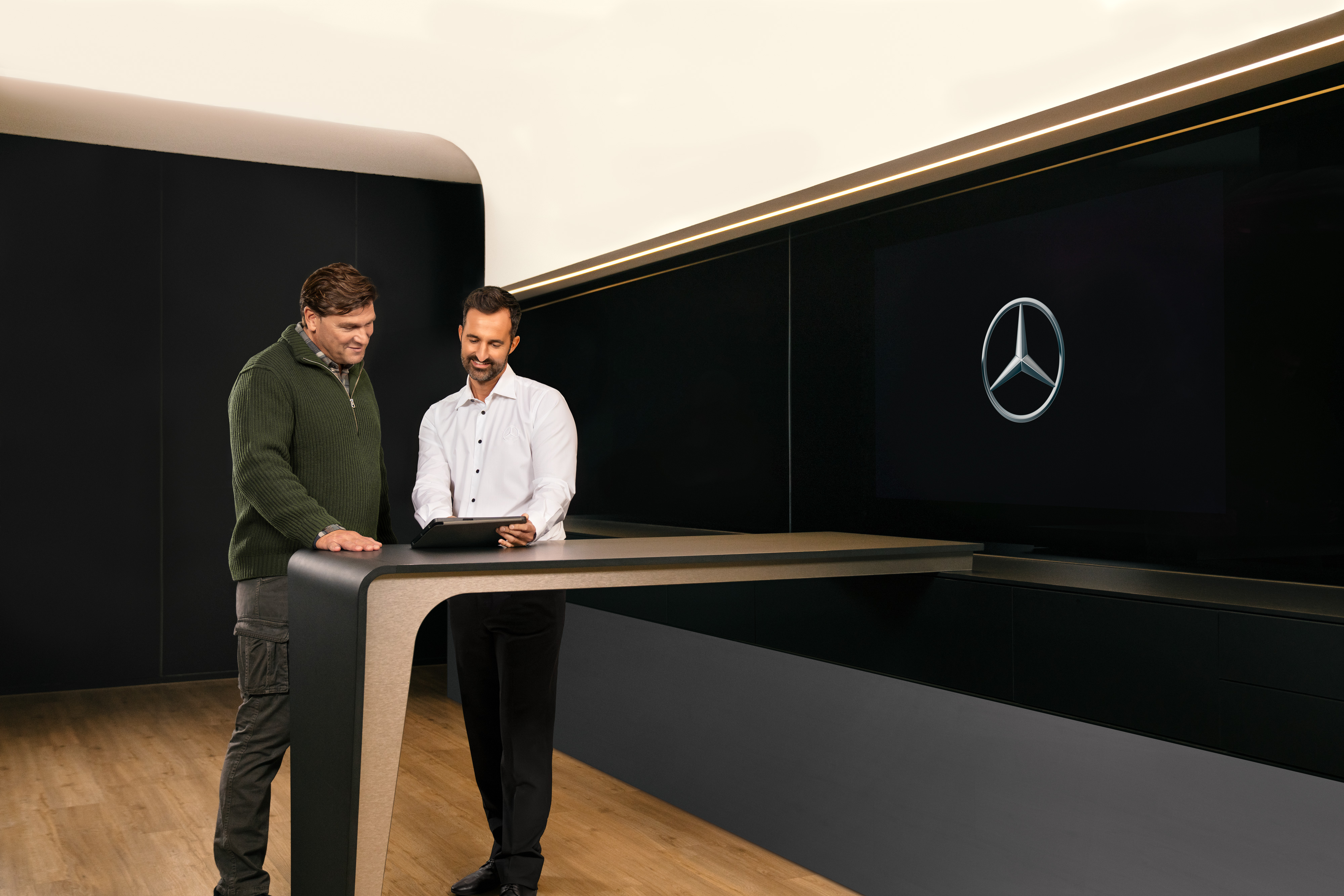 Mercedes-Benz | ServiceCare pro dodávková vozidla Dva muži stojí kolem stolu, konzultují a přitom se dívají na iPad.