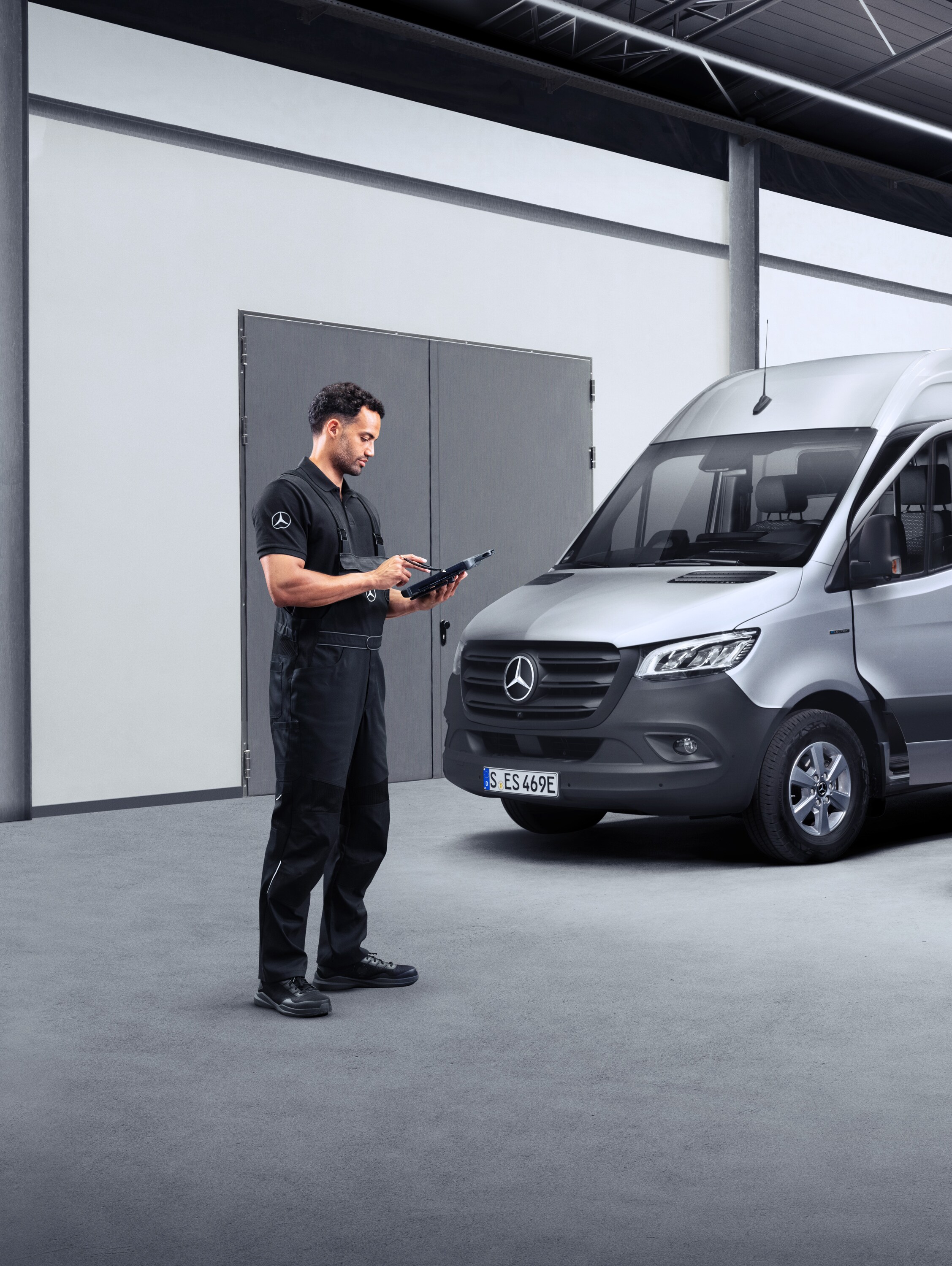Technik s&nbsp;tabletem před dvěma elektrickými dodávkovými vozidly