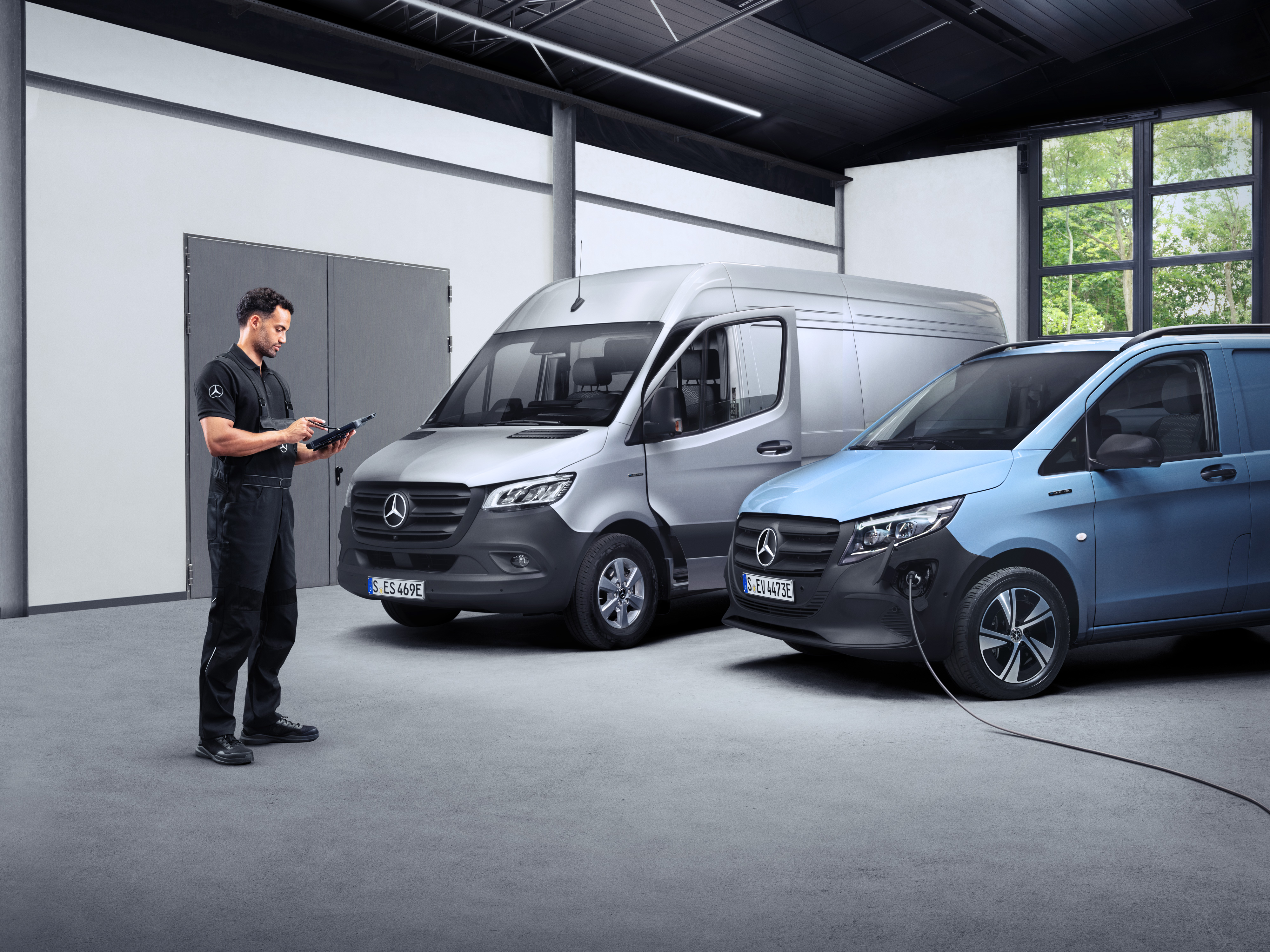 Mercedes-Benz | ServiceCare pro dodávková vozidla Technik s tabletem před dvěma elektrickými dodávkovými vozidly