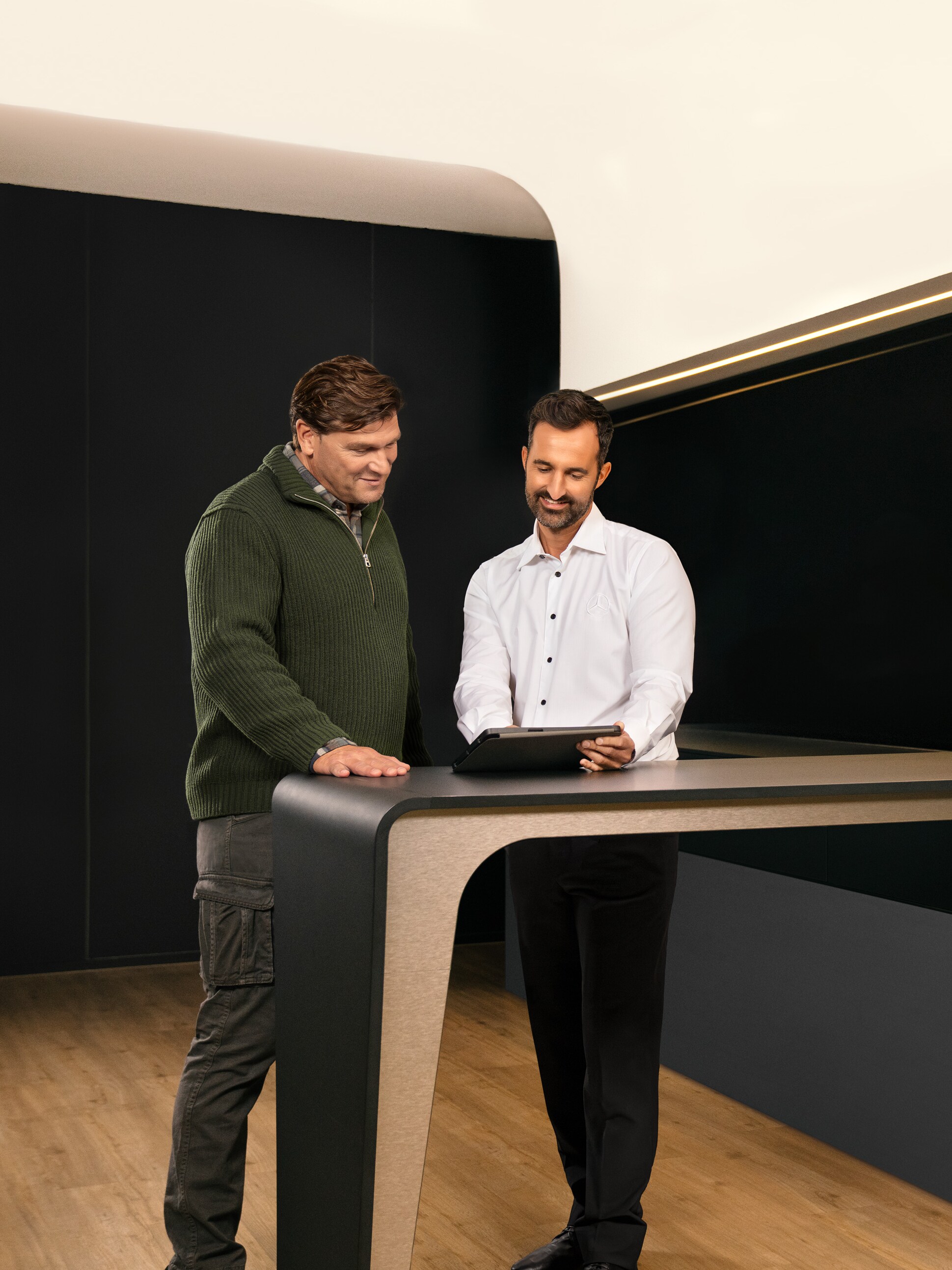 Dva muži diskutují nad tabletem o&nbsp;servisu užitkových vozidel od společnosti Mercedes-Benz.