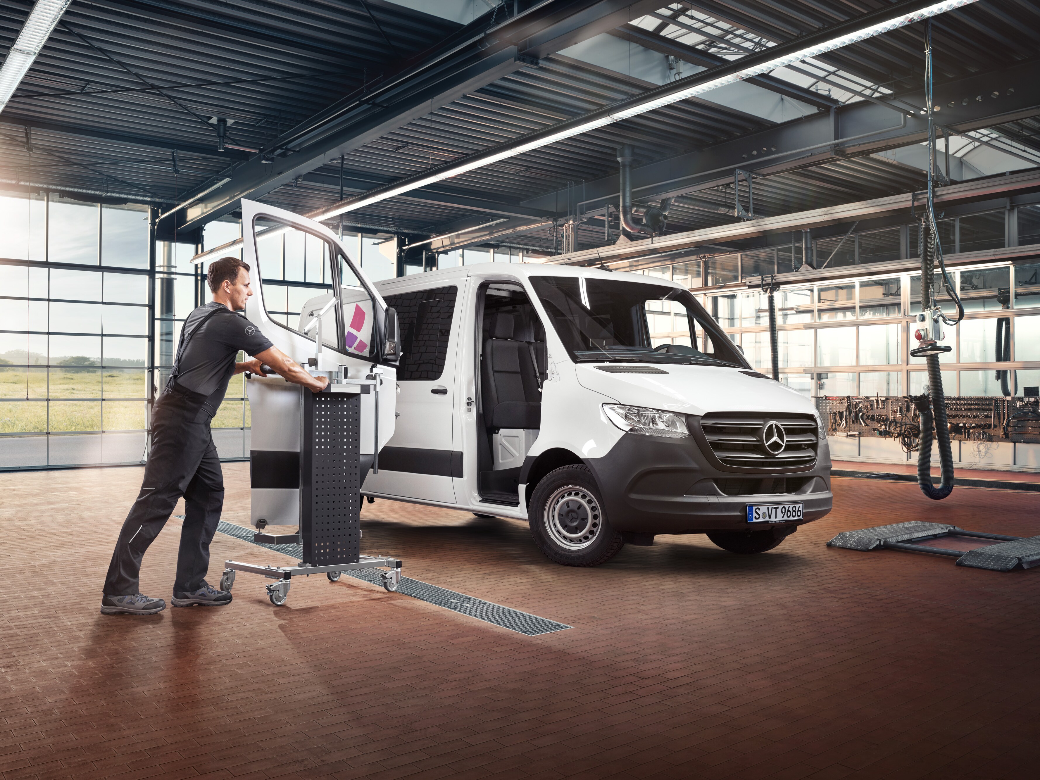 Technik provádí údržbu dveří spolujezdce u&nbsp;bílého dodávkového vozidla Mercedes-Benz Sprinter.