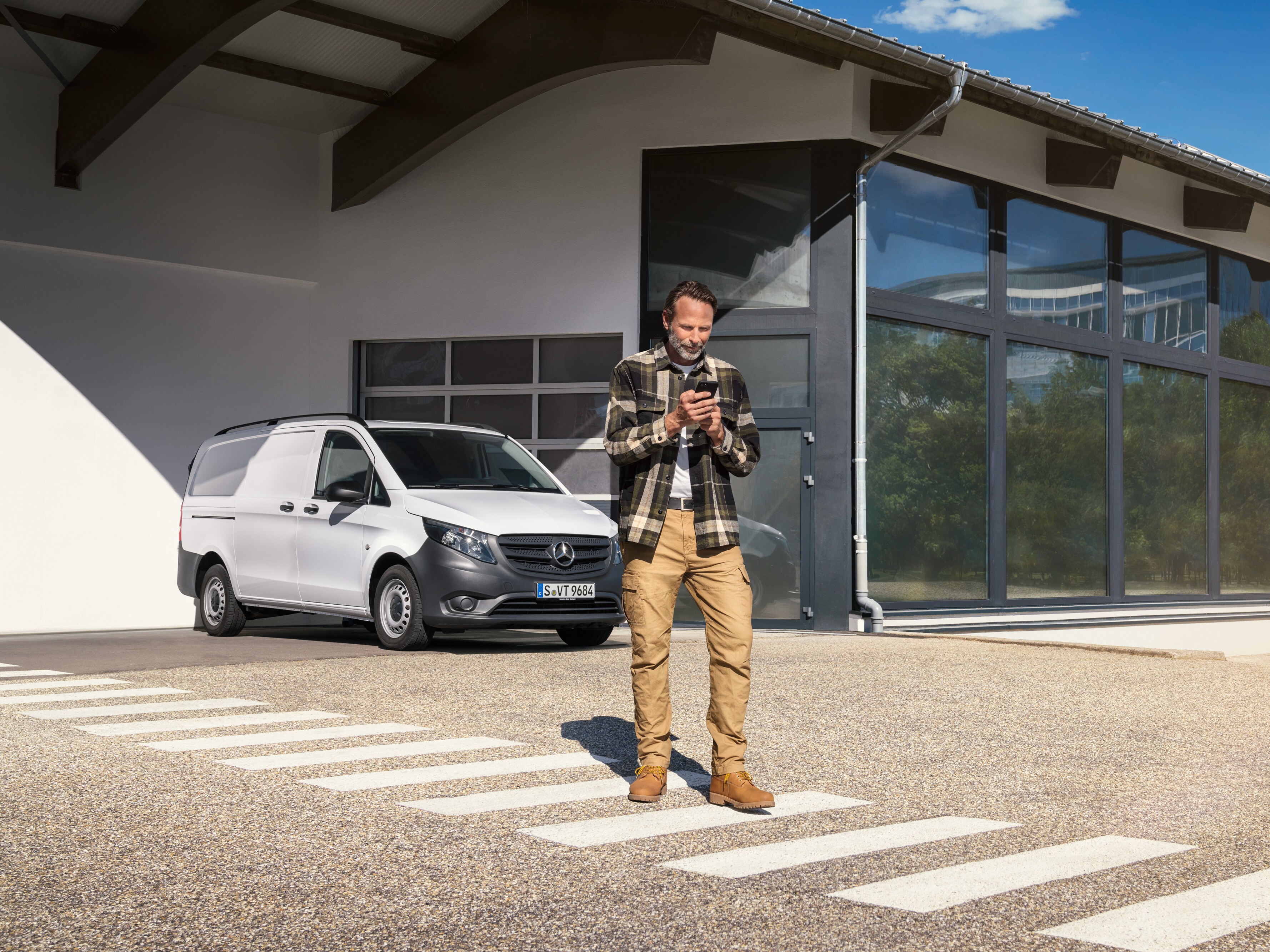 Muž stojící před bílým dodávkovým vozidlem Mercedes-Benz Vito a&nbsp;používající svůj chytrý telefon.
