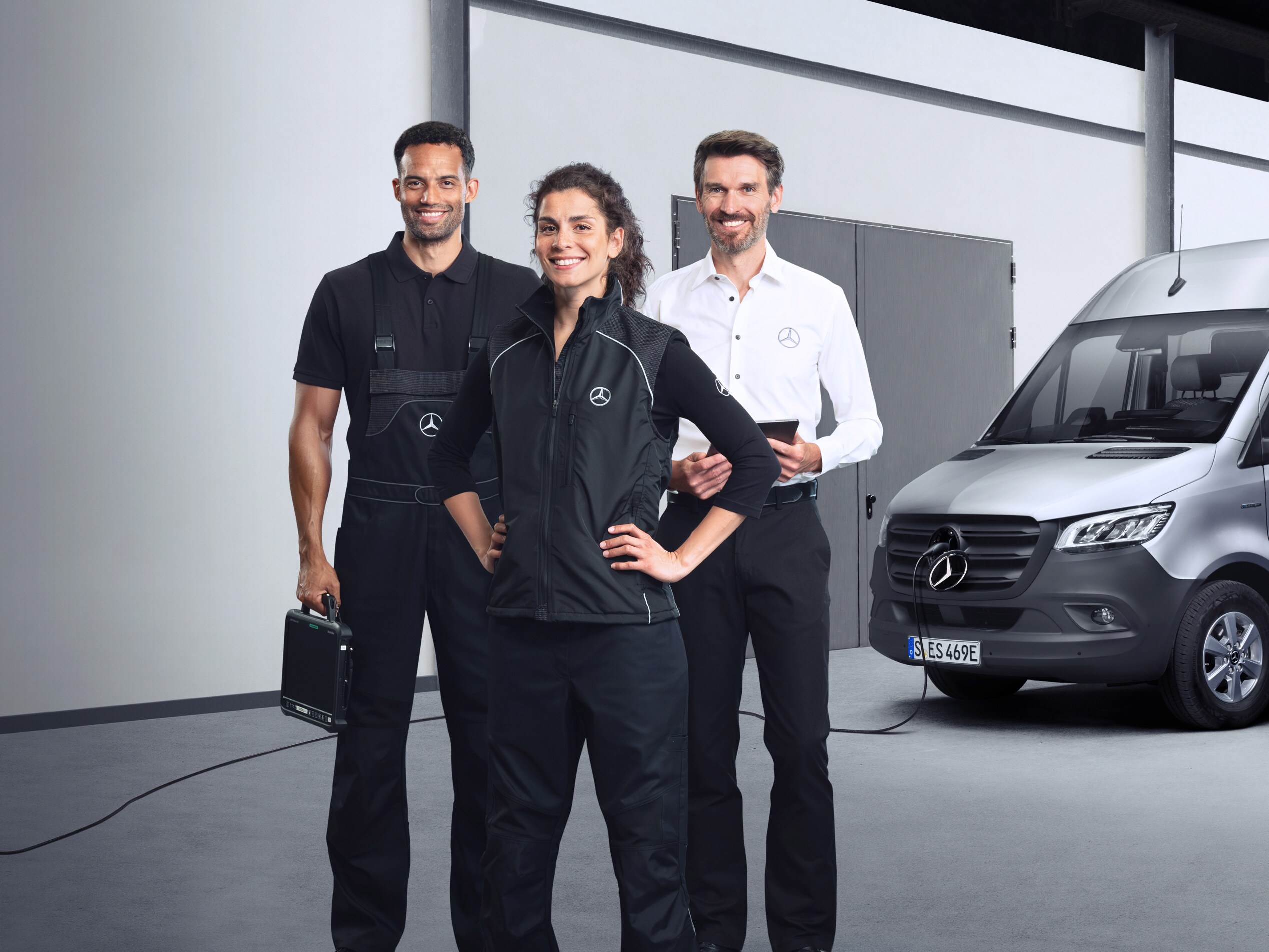 Tři zaměstnanci před elektrickým dodávkovým vozidlem Mercedes-Benz Sprinter s&nbsp;připojeným nabíjecím kabelem.