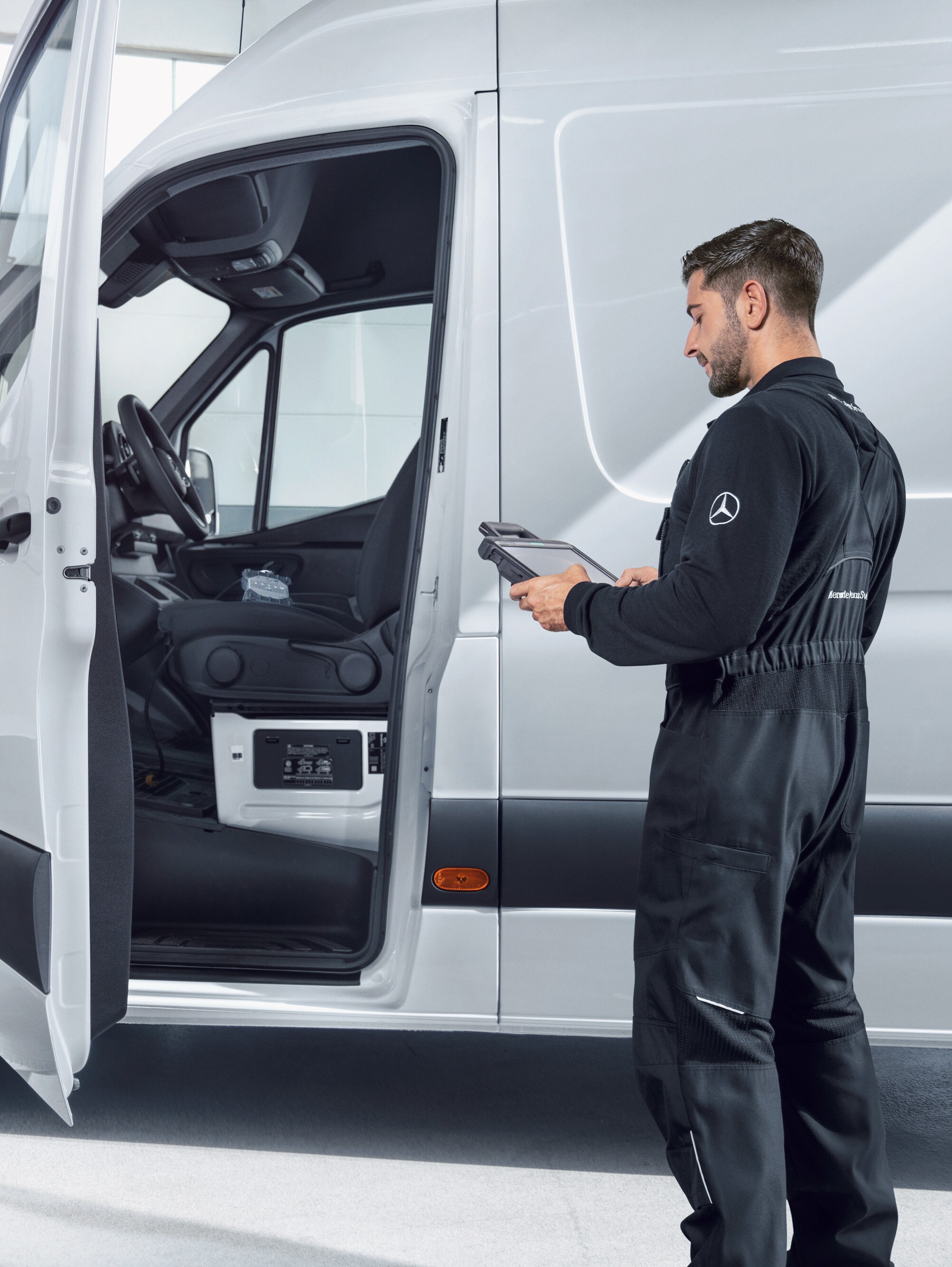 Technik s&nbsp;tabletem kontroluje bílé dodávkové vozidlo Mercedes-Benz Sprinter.