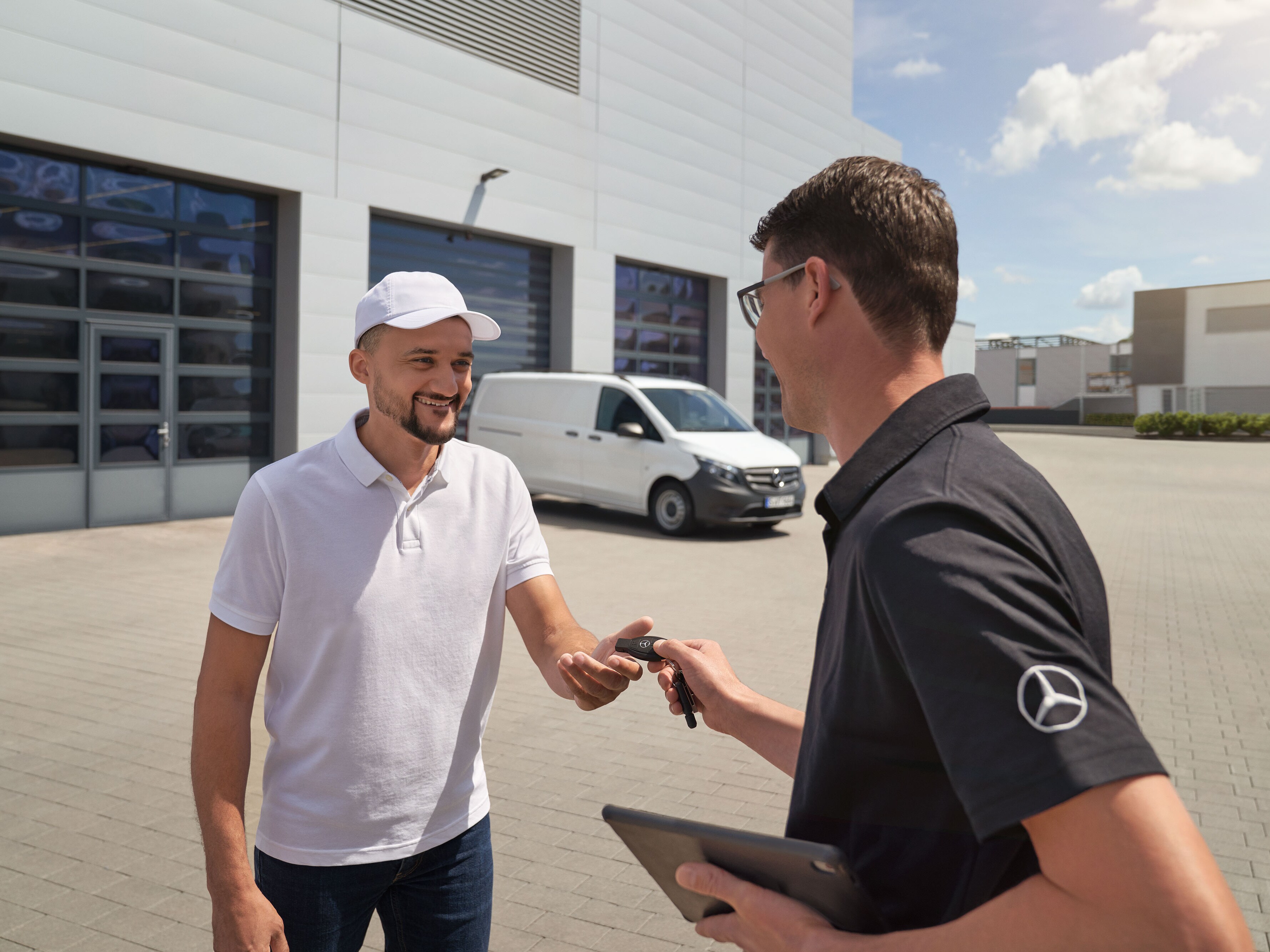 Servisní zástupce Mercedes-Benz předává klíčky zákazníkovi, v&nbsp;pozadí je bílé dodávkové vozidlo Mercedes-Benz Vito.