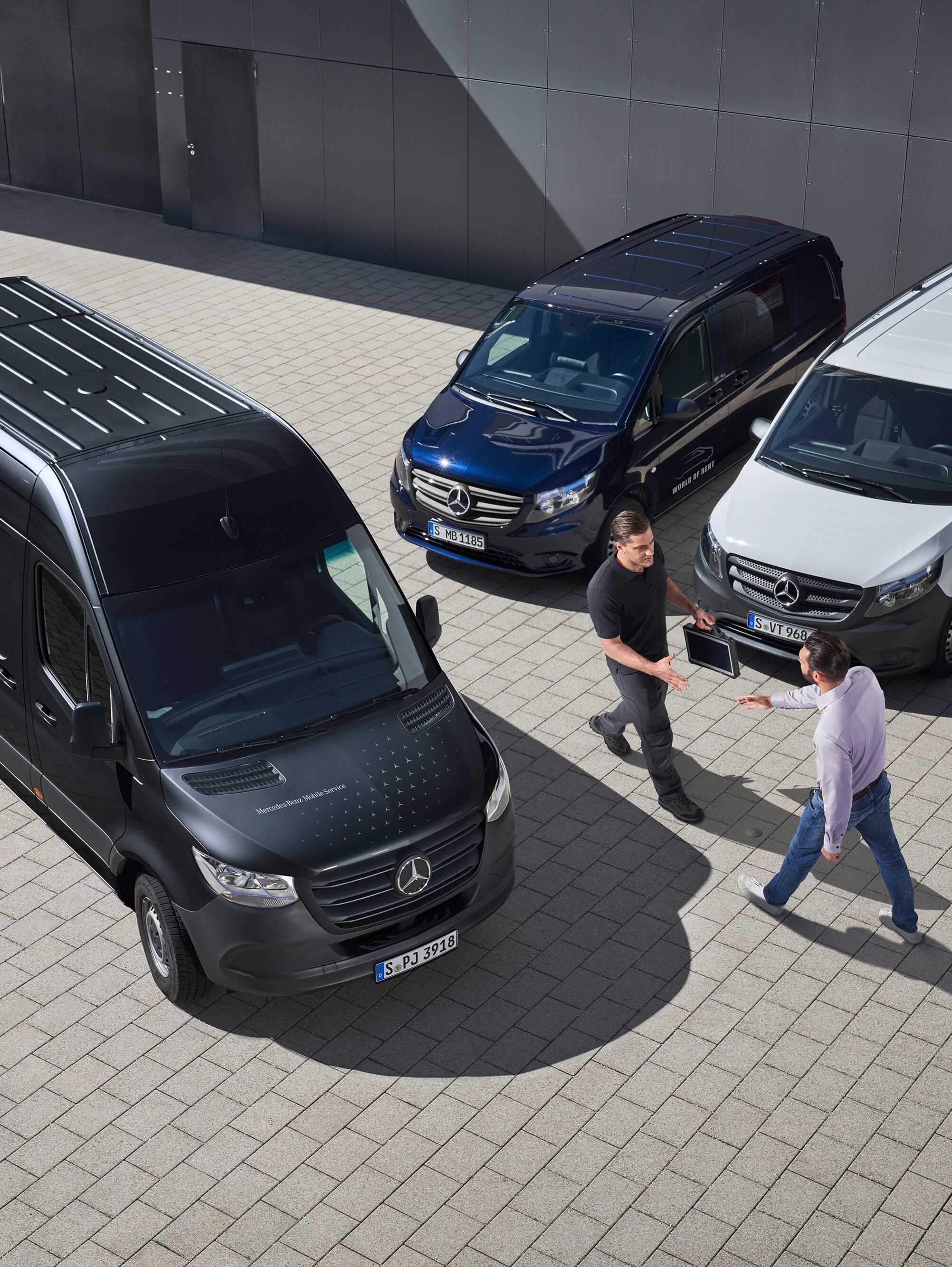 Dva muži se zdraví mezi dodávkovými vozidly Mercedes-Benz.