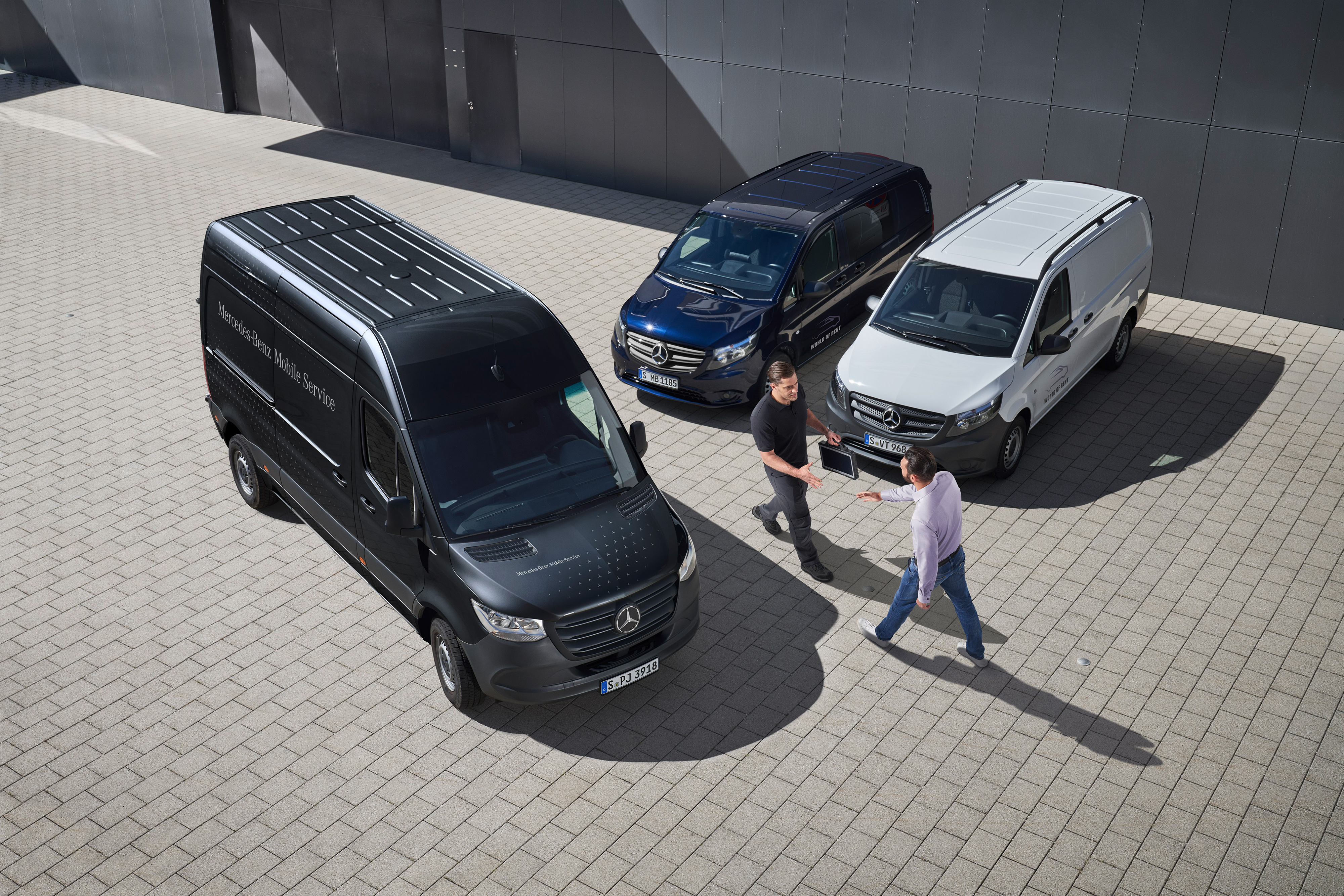 Mercedes-Benz | Přehled služeb | Mobilní servis Dva muži se zdraví mezi dodávkovými vozidly Mercedes-Benz.