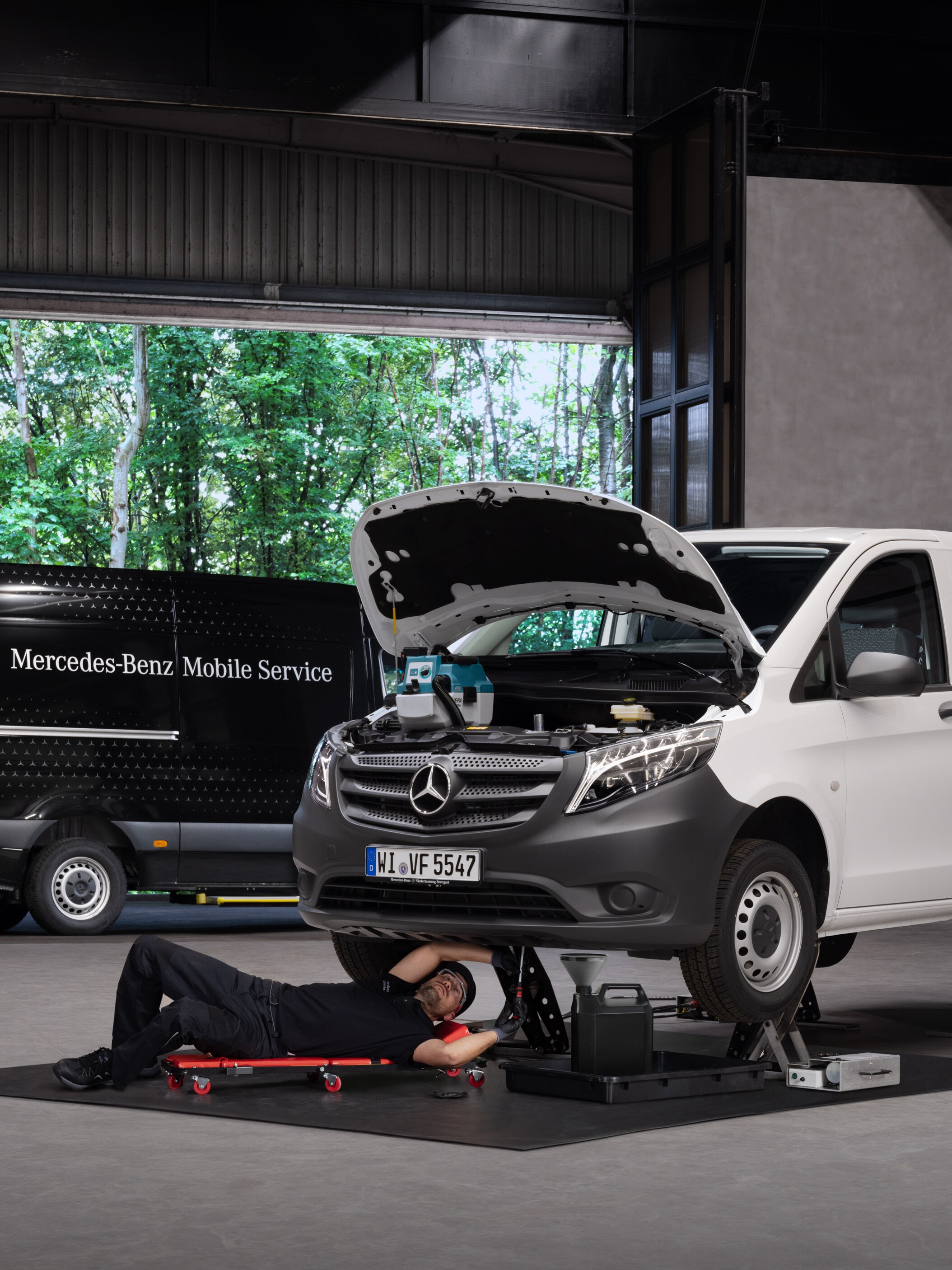 Technik opravuje bílé dodávkové vozidlo Mercedes-Benz Vito.