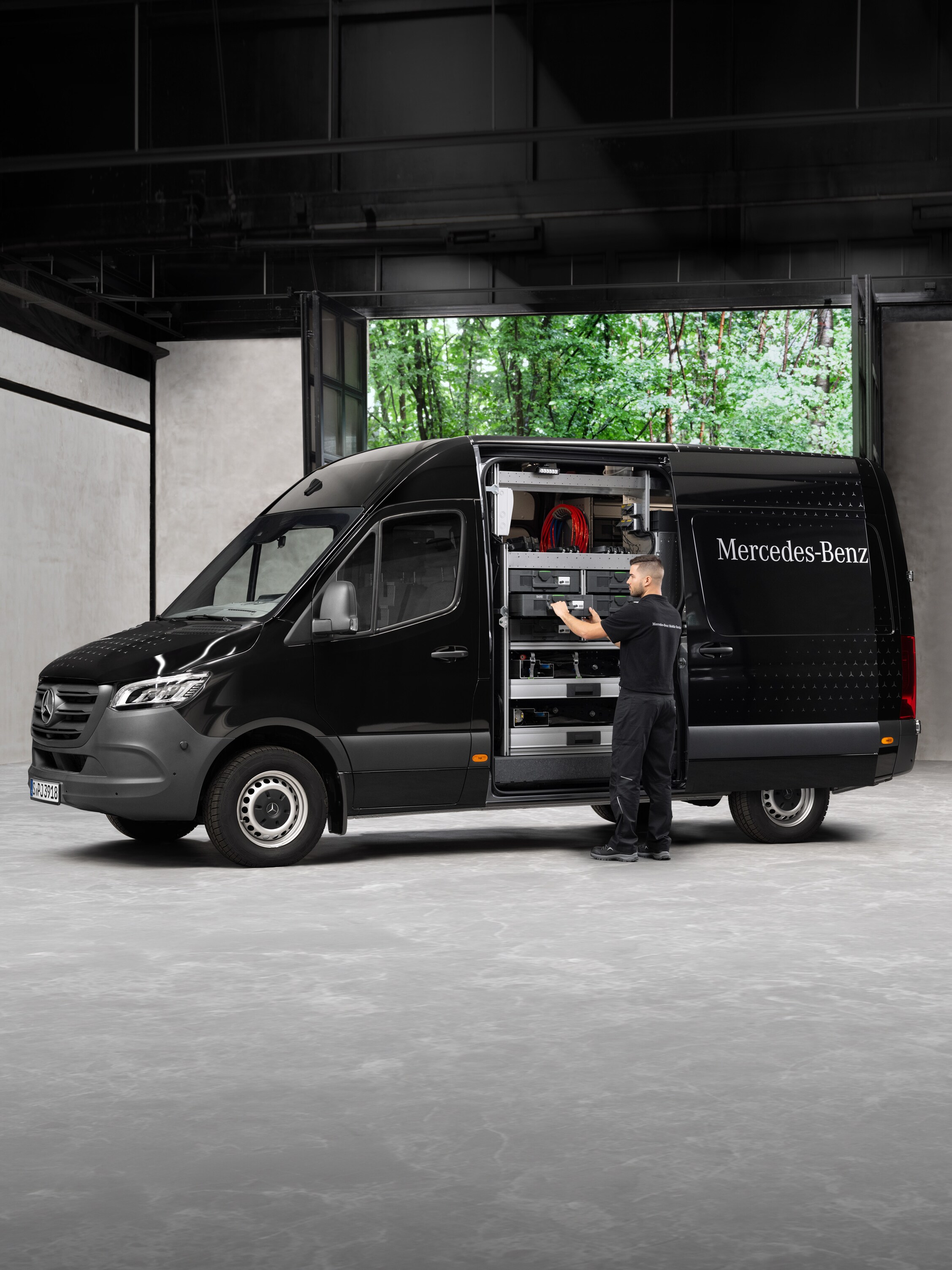 Technik vyndává nářadí z&nbsp;černého dodávkového vozidla Mercedes-Benz Sprinter.