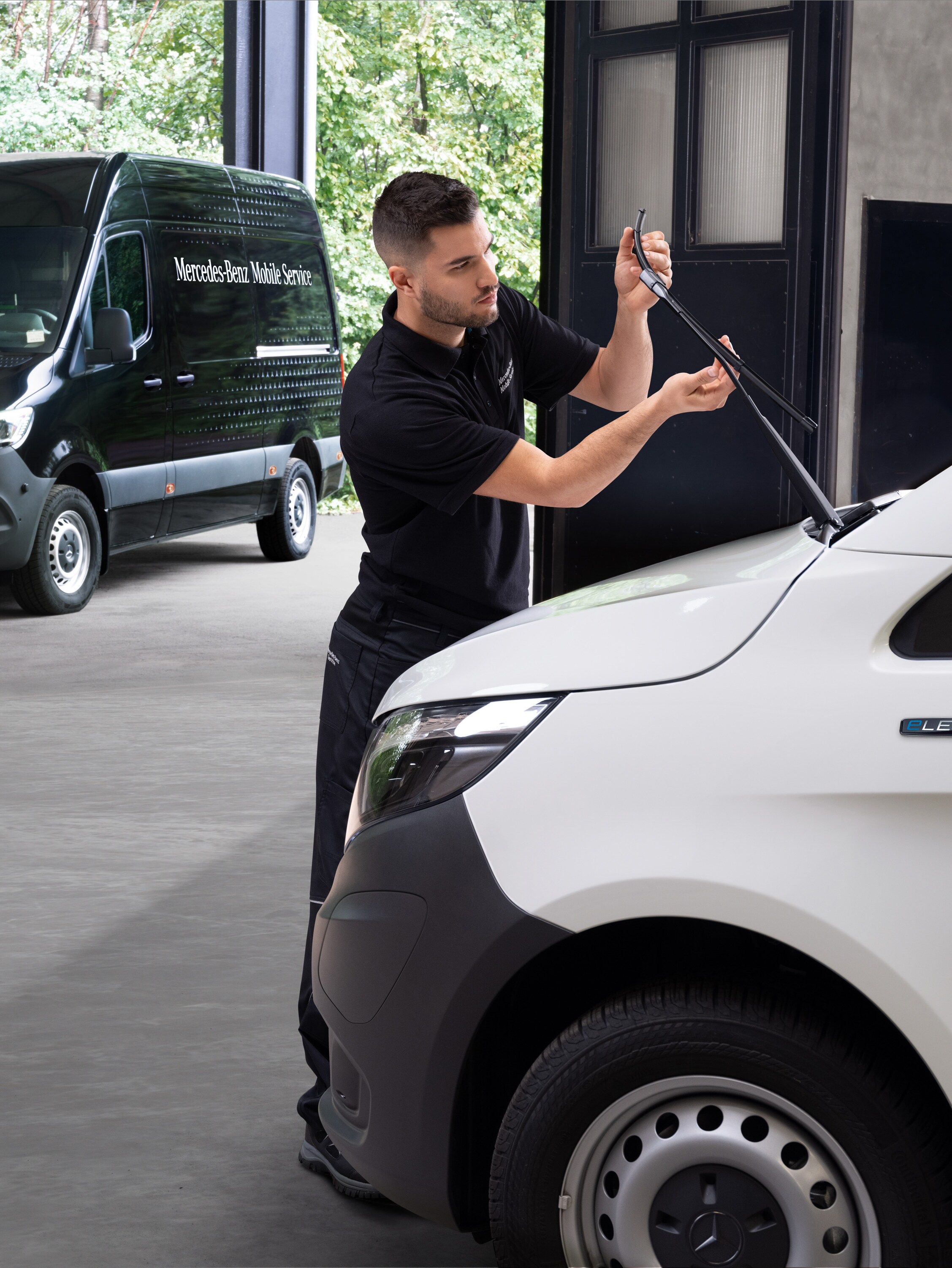 Technik mění stírátka u&nbsp;bílého dodávkového vozidla Mercedes-Benz Vito.