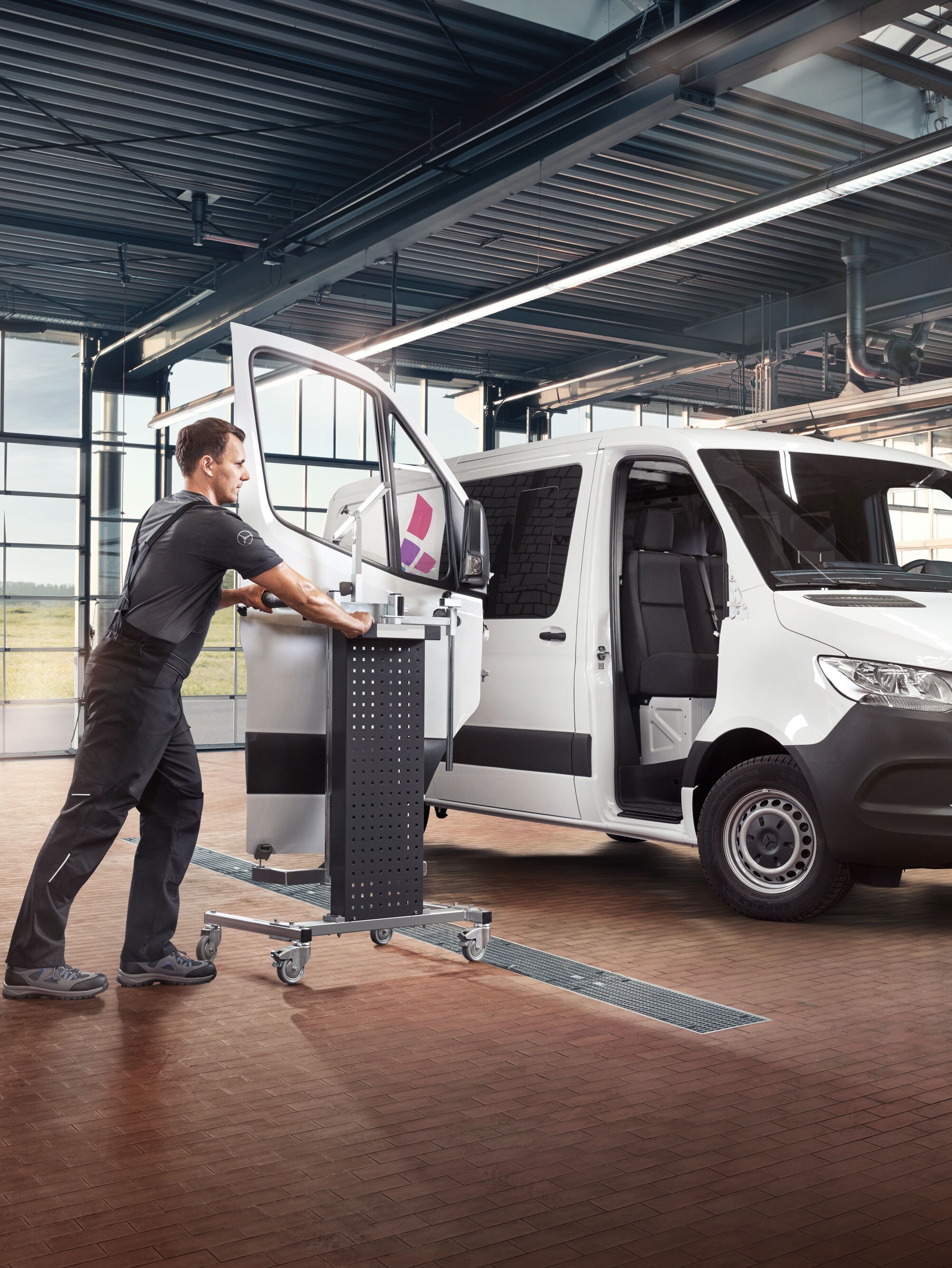 Mechanik montující dveře na bílé dodávkové vozidlo Mercedes-Benz Sprinter.