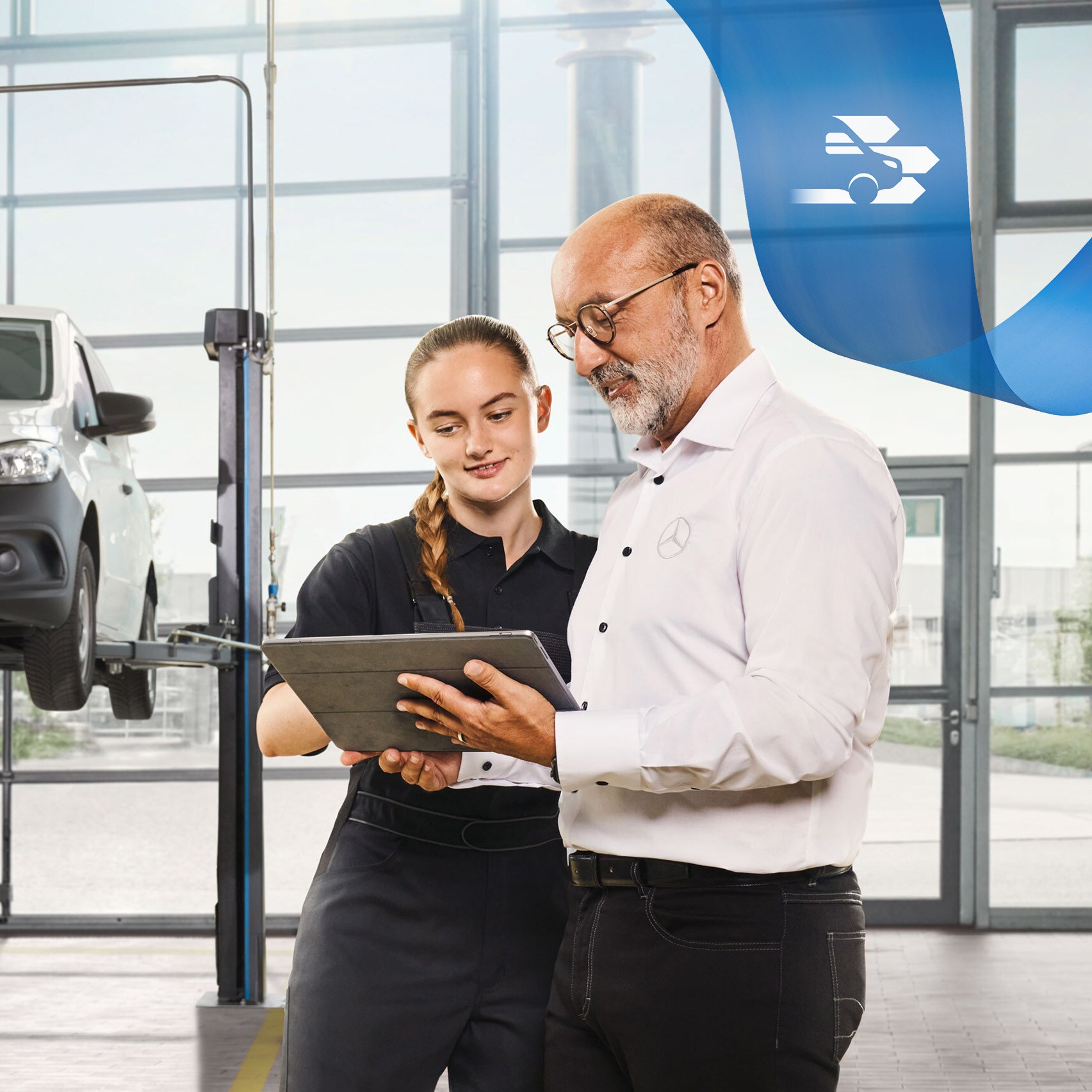 Dva zaměstnanci diskutují v&nbsp;dílně o&nbsp;servisu užitkového vozidla u&nbsp;zvednutého dodávkového vozidla Mercedes-Benz.