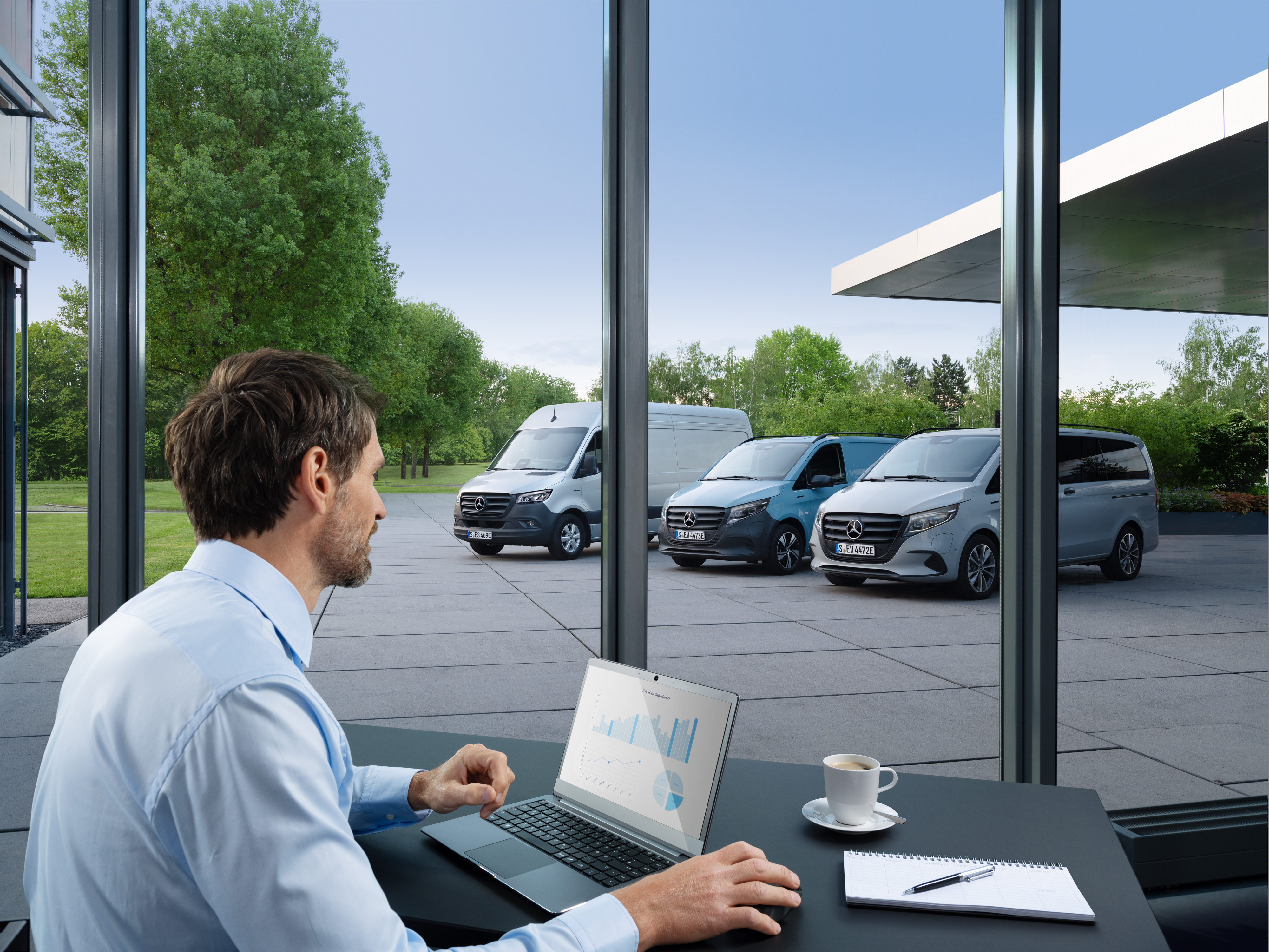 Mercedes-Benz | Technologie dodávkových vozidel | Van Uptime Monitor Muž monitorující několik zaparkovaných dodávkových vozidel Mercedes-Benz pomocí notebooku, symbol digitální správy vozového parku.