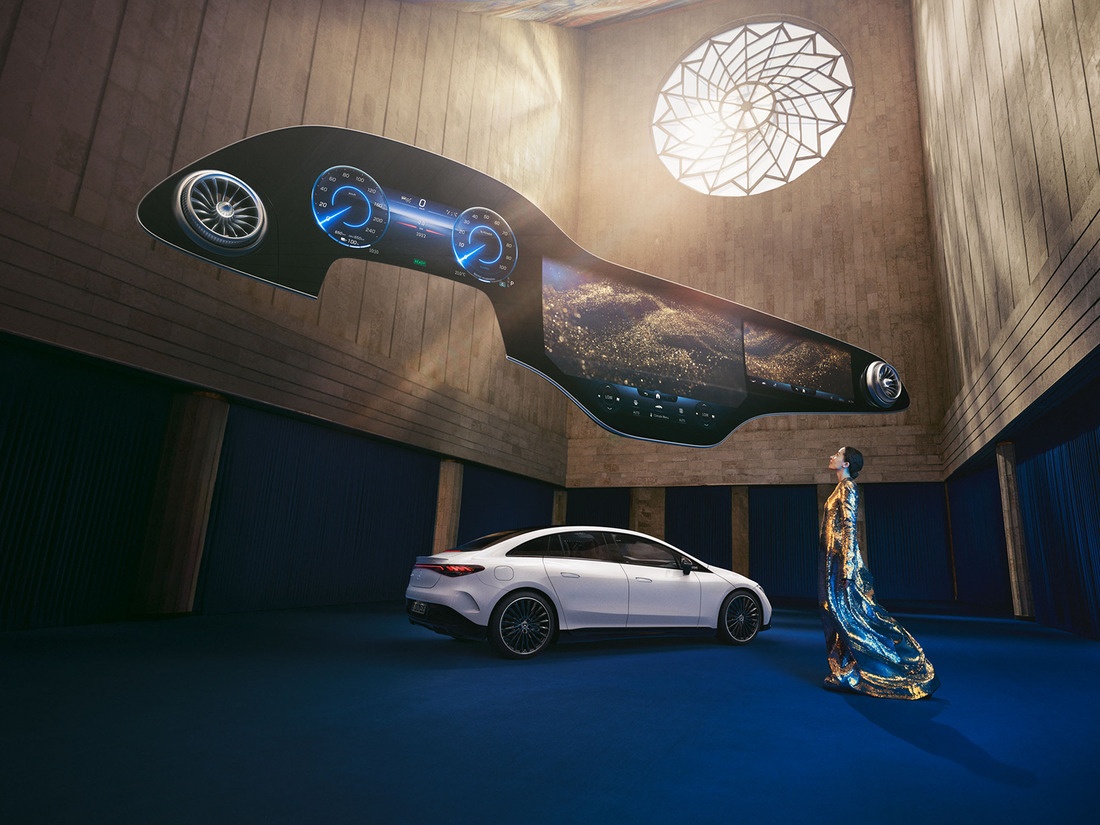 Žena stojící před vozidlem Mercedes-Benz EQ se vznášející se Hyperscreen nahoře. Mercedes-Benz Hyperscreen